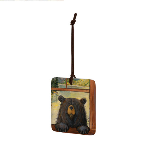 A square ceramic hanging ornament with a painting of a black bear peeking in a window, displayed angled to the left.