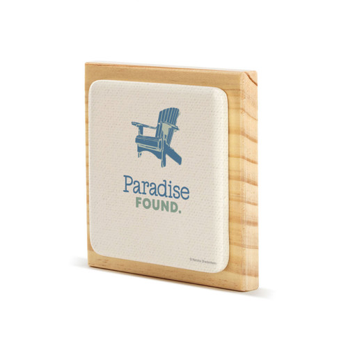 A square wood plaque with a tile attached that has a blue Adirondack chair and says "Paradise Found" on an angle to the left.