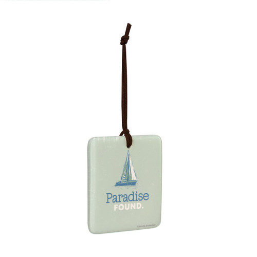 A square hanging ornament of a sailboat with the saying "Paradise Found" on a pale green background angled to the right.