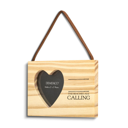 A rectangular hanging wood ornament with a heart shaped two inch photo opening next to the saying "The Beaches are Calling" under two black lines with room for personalization, displayed angled to the left.