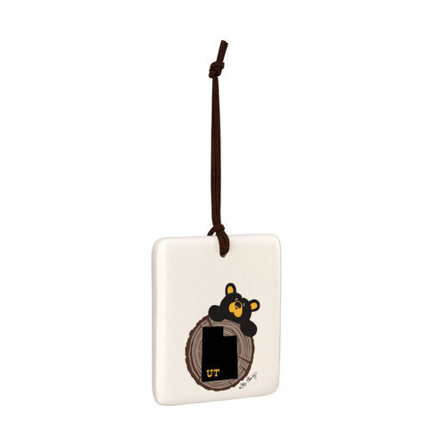 A white square hanging ornament with a black bear peeking over a tree stump with Utah on it, displayed angled to the right.