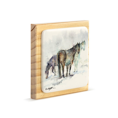 A square wood plaque angled to the right with a tile attached that has a watercolor image of three horses.
