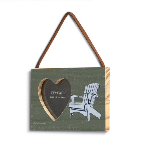 A dark green rectangular hanging wood frame with a 2 inch heart shaped opening for a photo next to a light blue Adirondack chair shown on an angle to the left.