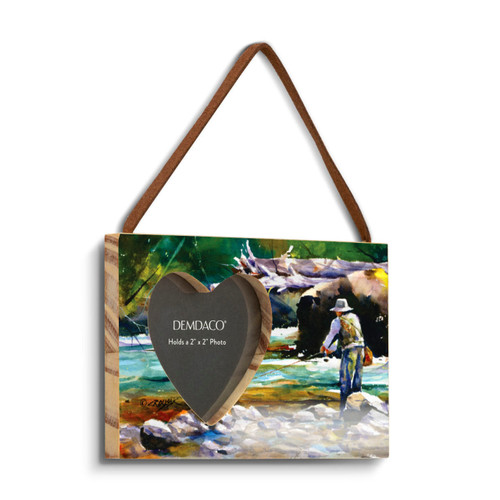 A rectangular wood hanging frame with a heart shaped 2 inch photo opening next to a watercolor image of a man fishing in a river, displayed angled to the right.