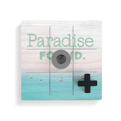 A square wood board for tic tac toe with a lake scene that says "Paradise Found" with a gray O and black X displayed on top.