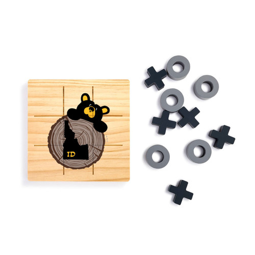 A square wood tic tac toe board with a black bear looking over a tree stump with Idaho on it, next to a set of X's and O's in gray and black.