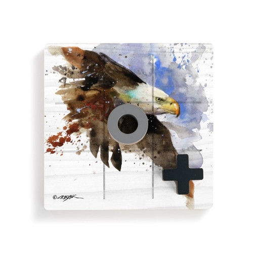 A square wood tic tac toe board with a watercolor image of a bald eagle in flight, displayed with a gray O and black X on top.