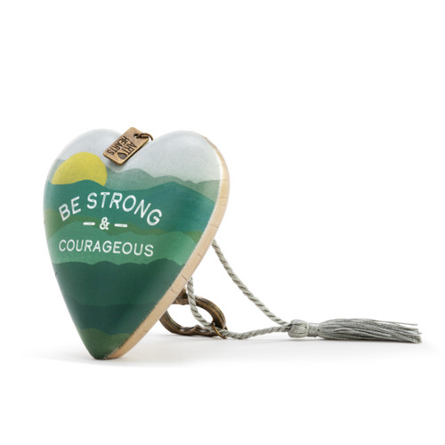 Heart shaped sculpture with a silver tassel and metal key attached. The heart has a green mountain scene and says "Be Strong & Courageous", displayed angled to the left.