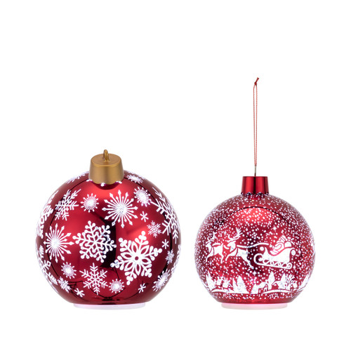 Profile view of two different red round ornaments. The large one has white snowflakes and the small has a scene of Santa in his sleigh over the town.