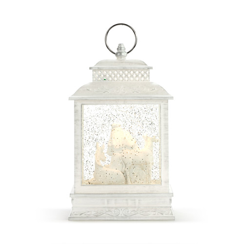 Back view of a whitewashed lit lantern with a white nativity scene inside.