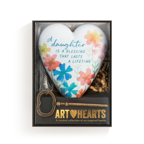 Heart shaped sculpture with a silver tassel and metal key attached. The heart has colored flowers and says "A daughter is a Blessing that Lasts A Lifetime", displayed in a packaging box.