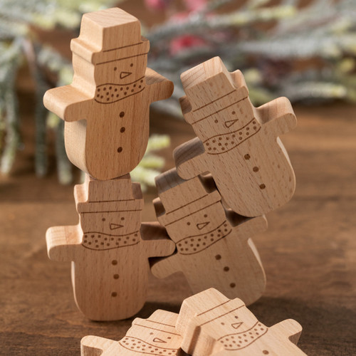 A close up cropped view of a set of six wood snowmen used for a balance stacking game, displayed on a wood table with four of them stacked together.