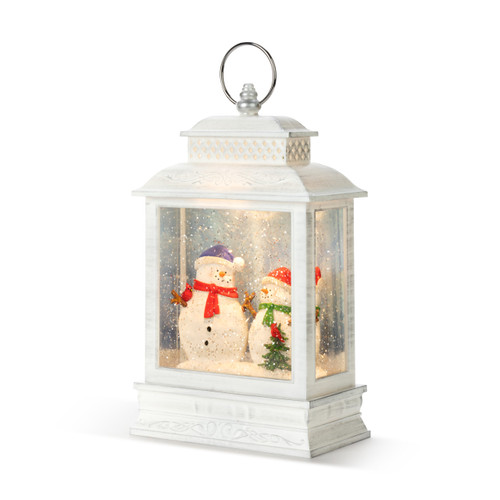 White lit lantern with two snowmen inside by a small tree with a cardinal, displayed angled to the left.