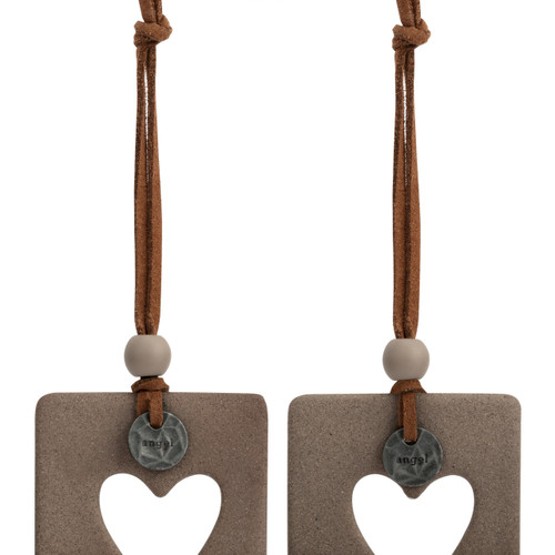 Detail view of the metal token on a set of two hanging tan and white ceramic ornaments with a heart cutout and metal tokens that say "angel". One ornament says "guide us and keep us safe" and the other says "protect and watch over us".