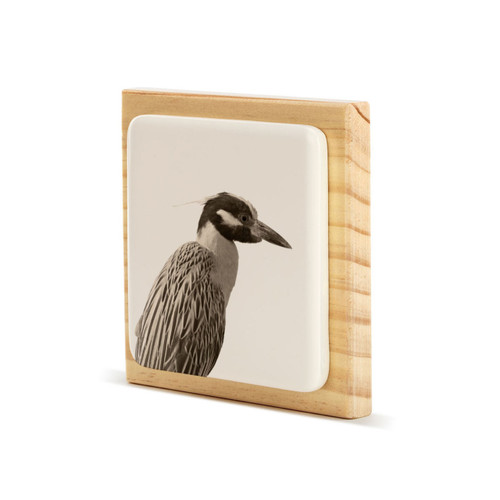 A square wood plaque with a white tile that has an image of a heron, displayed angled to the left.