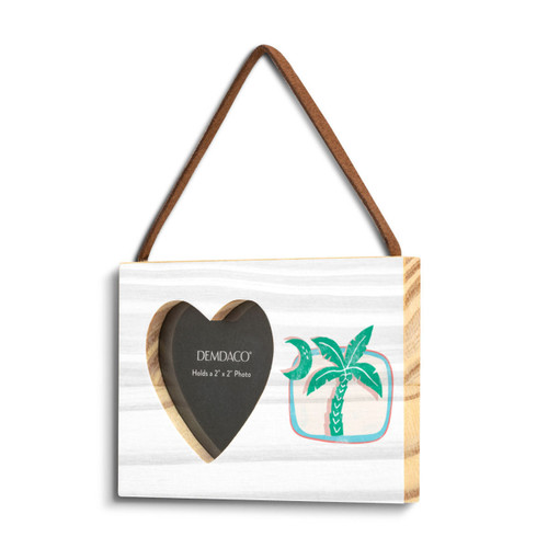 A rectangular hanging white wood frame ornament with a graphic image of a green moon and palm tree with a 2x2 heart shaped opening for a photo, displayed angled to the left.