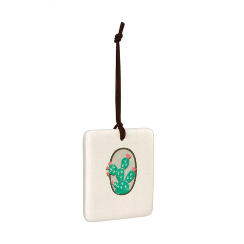 A square hanging tile ornament with a graphic image of a green cactus with pink flowers on a tan background, displayed angled to the right.