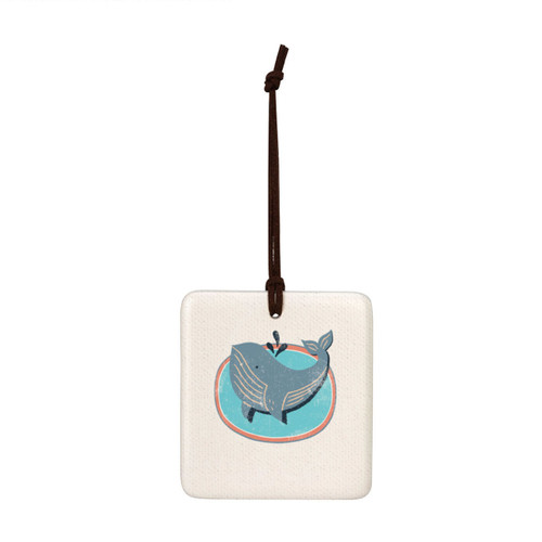 A square hanging tile ornament with a graphic image of a gray whale on a sea blue background.