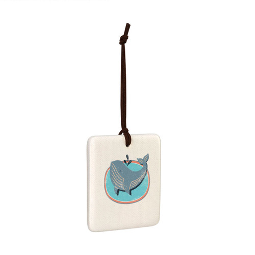 A square hanging tile ornament with a graphic image of a gray whale on a sea blue background, displayed angled to the right.