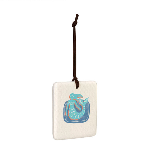 A square hanging tile ornament with a graphic image of a light blue mermaid on a blue background, displayed angled to the right.
