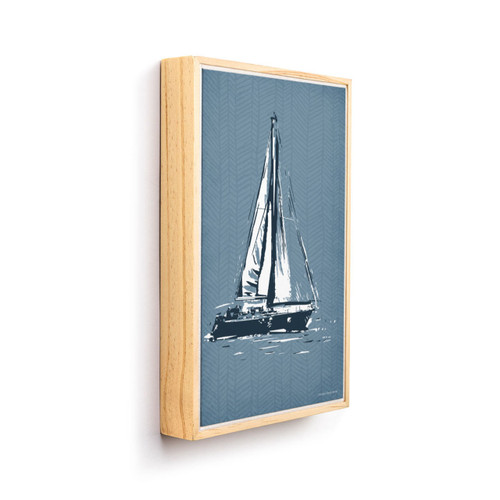 A graphic art image of a black and white sailboat on a blue background in a light wood frame and angled to the right.