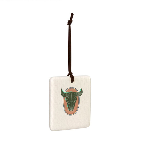 A square hanging tile ornament with a graphic image of a horned animal skull on a peach background, displayed angled to the right.