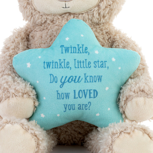 Detail view of the blue star on a brown plush musical bear holding a blue star that says "Twinkle, twinkle, little star, Do you know how Loved you are?".