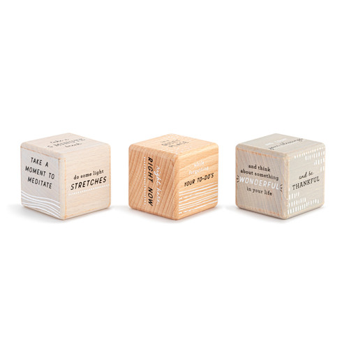 A set of three wood dice with messages about self care on each side that create different message when read together, displayed with other sides showing different messages.
