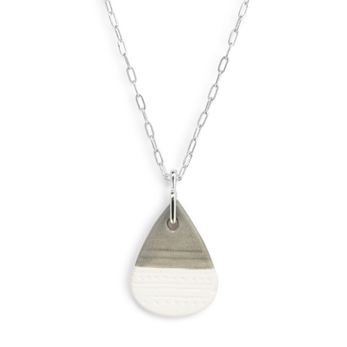 Detail view of the charm on an adjustable silver chain necklace with a teardrop shaped gray and white diffuser charm.