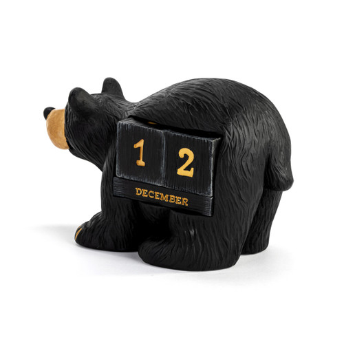 A perpetual calendar made of two number blocks and a month block that fit into the side of a standing black bear figurine, displayed angled to the left.