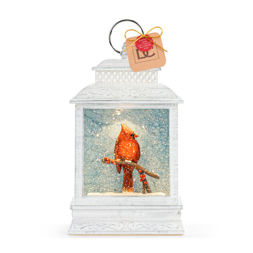 A white lit musical lantern with the image of a red cardinal on a branch inside, displayed with a product tag attached.