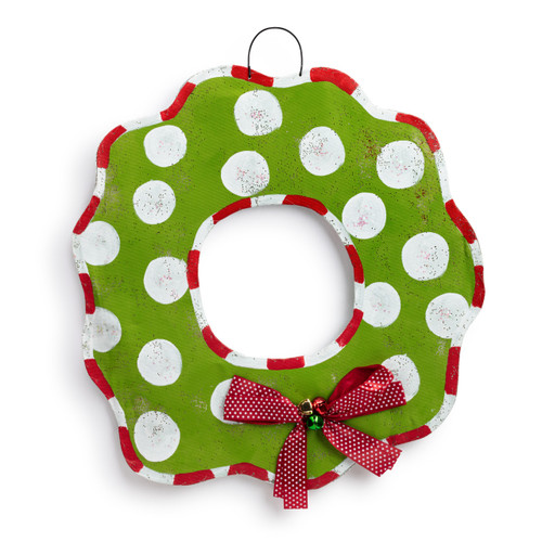 Back view of a reversible wreath shaped metal door hanger that is green with large white dots and a red bow with small white dots.