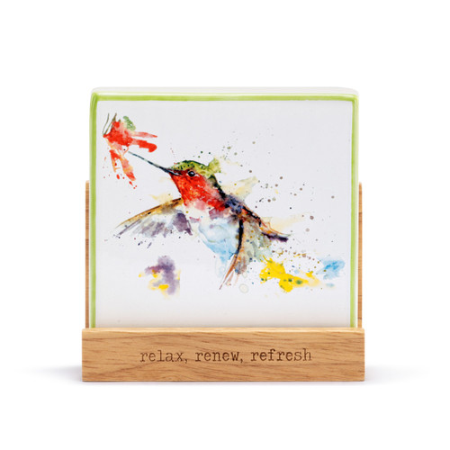 A square oil diffuser with a watercolor image of a hummingbird on it set in a wood stand that says "relax, renew, refresh".