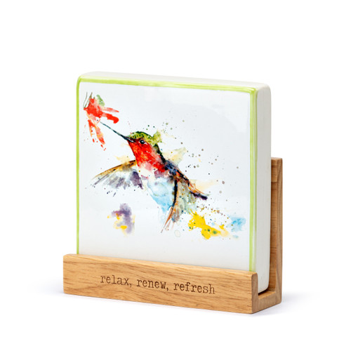 A square oil diffuser with a watercolor image of a hummingbird on it set in a wood stand that says "relax, renew, refresh", displayed angled to the left.