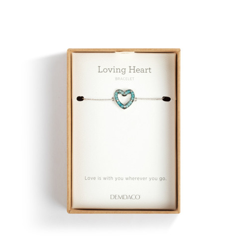 An adjustable silver chain bracelet with a heart shaped charm filled with small aqua stones, displayed in a packaging box.