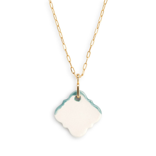 Detail view of the backside of a charm on an adjustable gold chain necklace with a diamond shaped blue and white diffuser charm.