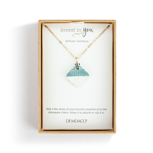 An adjustable gold chain necklace with a diamond shaped blue and white diffuser charm, displayed in a packaging box.