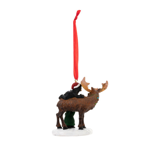 Back view of a hanging ornament of a standing moose in the snow with two little black bears climbing on his back.