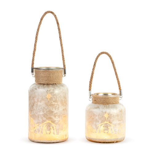 A set of two lit glass jars with the Nativity scene around the jar. The jar has jute wrapped around the neck of the jars and used for a handle.