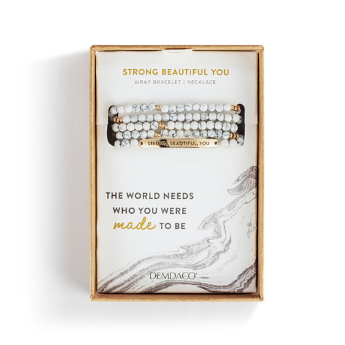 A multi-strand beaded bracelet in a mix of white with a gold metal bar that says "Strong, Beautiful, You", displayed in a packaging box.
