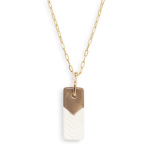 Detail view of the charm on an adjustable gold chain necklace with a vertical rectangular taupe and white diffuser charm.
