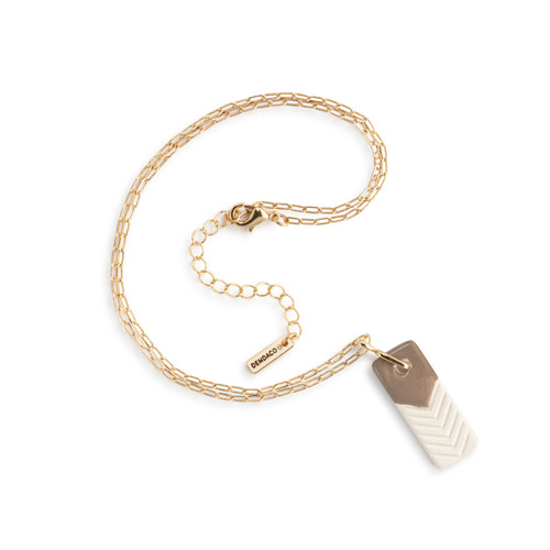 An adjustable gold chain necklace with a vertical rectangular taupe and white diffuser charm, displayed laid out on a white background.