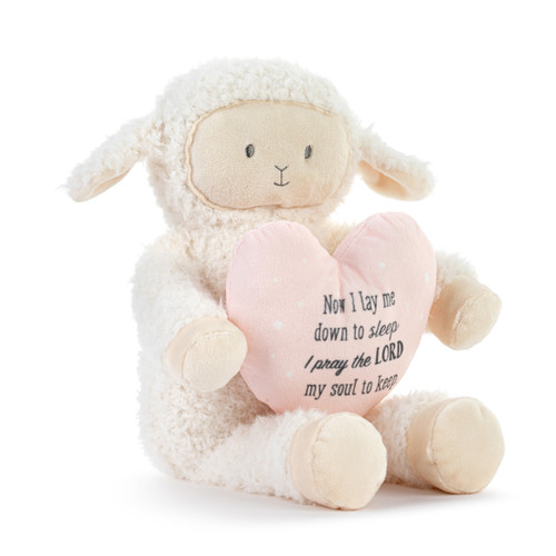 A cream plush musical lamb holding a light pink heart that says "Now I lay me down to sleep I pray the Lord my soul to keep", displayed angled to the right.