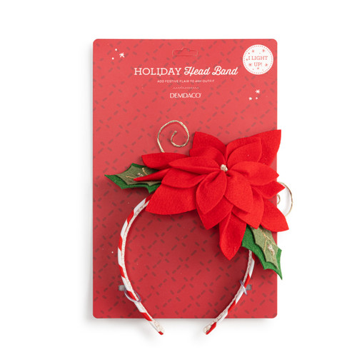 A red and white holiday headband with a red and green poinsettia on top, displayed on a packaging backer card.