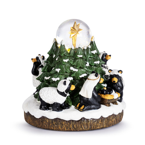 A musical snow globe with a black bear family in a Nativity scene among evergreens with a star in a glass ball at the top, displayed angled to the right.
