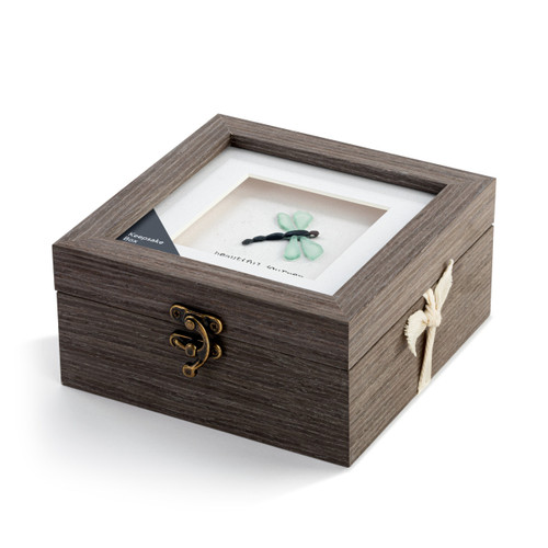 A square gray wood keepsake box with a metal clasp. The top has pebble art of a dragonfly and says "beautiful journey", displayed angled to the left with a product tag and ribbon.