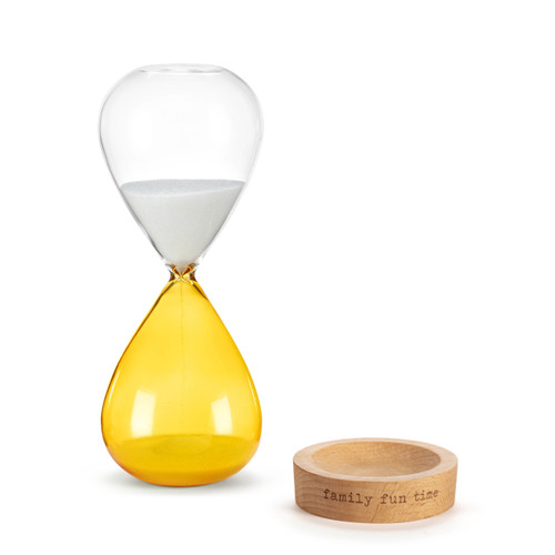 A glass sand timer with yellow glass on the bottom half sitting in a wood base that reads "family fun time", displayed with the glass timer off the wood base.