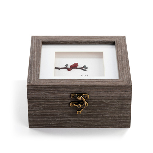 Front facing view showing the clasp on a square gray wood keepsake box with a metal clasp. The top has pebble art of a red bird on a branch that says "love".