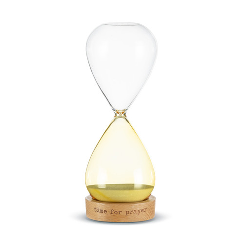 A glass sand timer with light yellow glass on the bottom half sitting in a wood base that says "time for prayer".