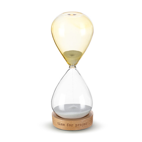 A glass sand timer with light yellow glass on the bottom half sitting in a wood base that says "time for prayer", displayed with the clear portion at the bottom and the light yellow at the top.